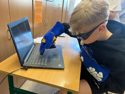 Uczeń w rękawicy pisze na komputerze.