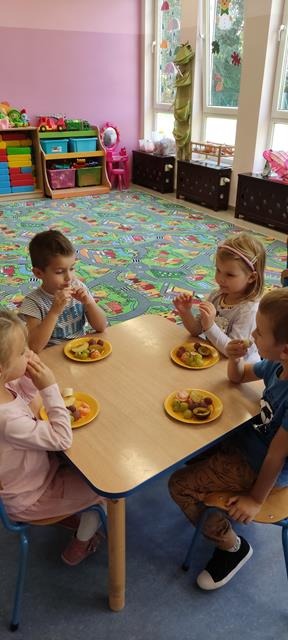 dzieci jedzą owoce przy stoliku