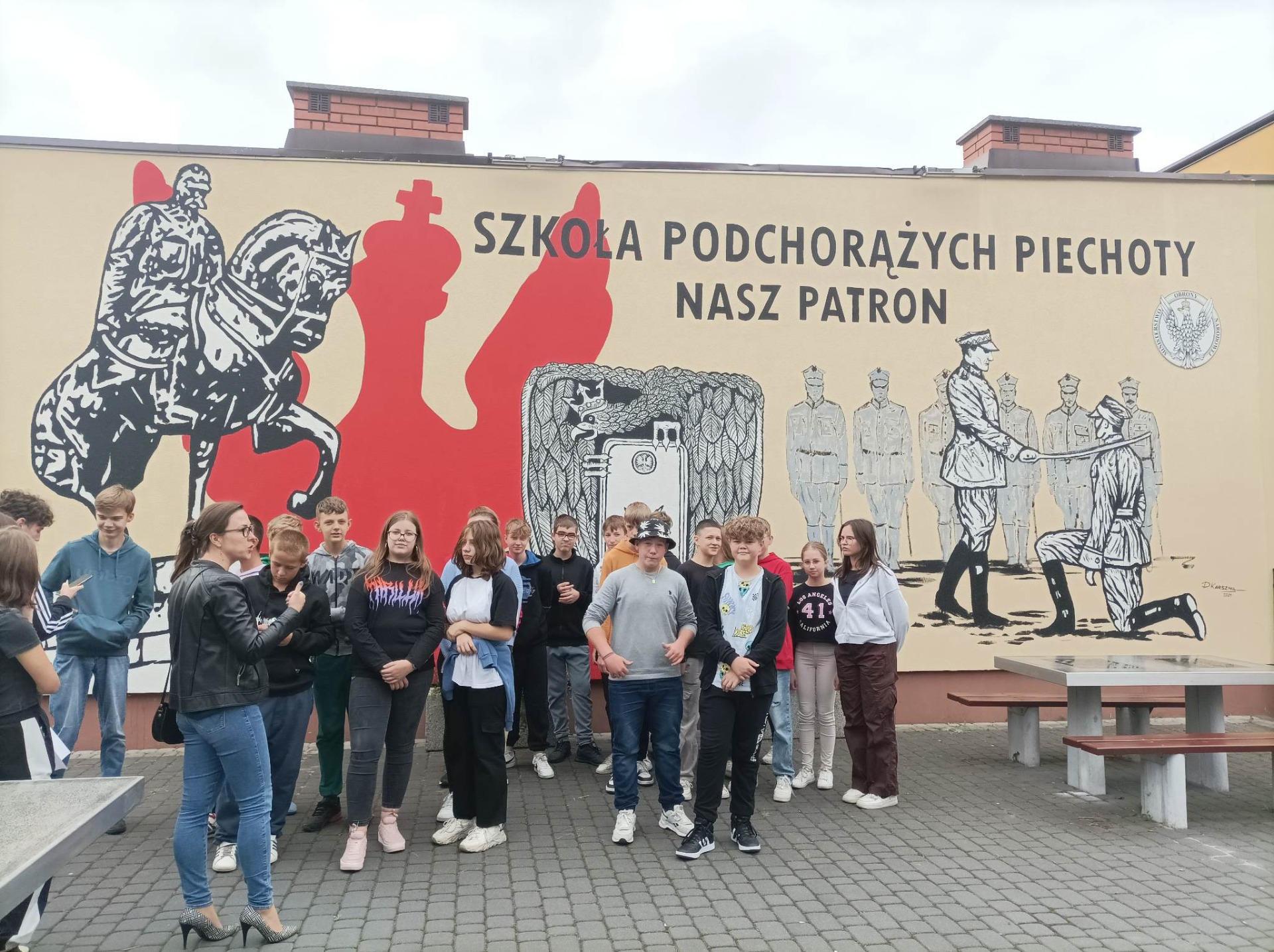 Grupa uczniów stoi pod muralem