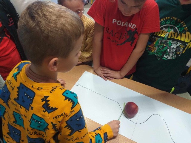 Dzieci turlają jabłko.