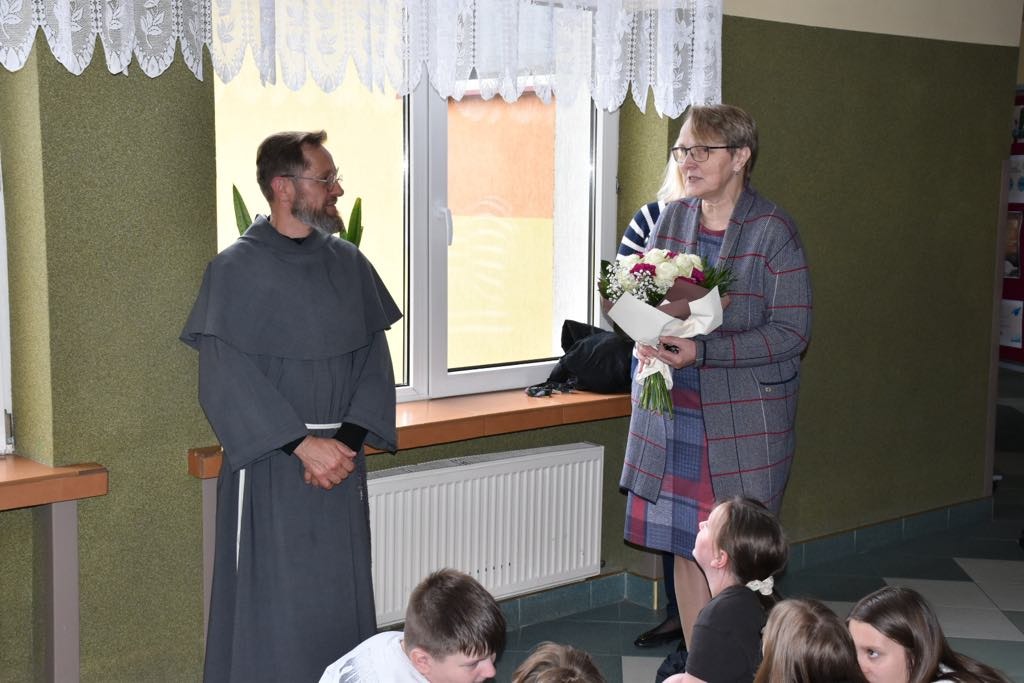 Franciszkanin ojciec Jarosław i dyrektor szkoły z bukietem kwiatów w ręku.